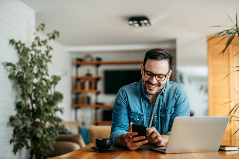 Happy man on phone after finding air conditioning maintenance checklist online. Gene's Heating & Air Conditioning, Plumbing & Electrical blog image.