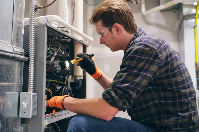 5 Reasons to Schedule a Fall Furnace Clean and Check. Tech in front of furnace.