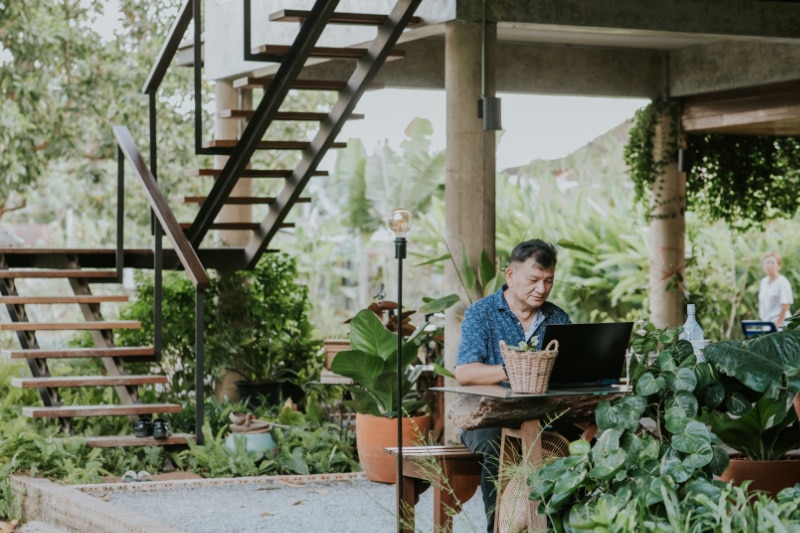 senior man working at home while using computer with family.