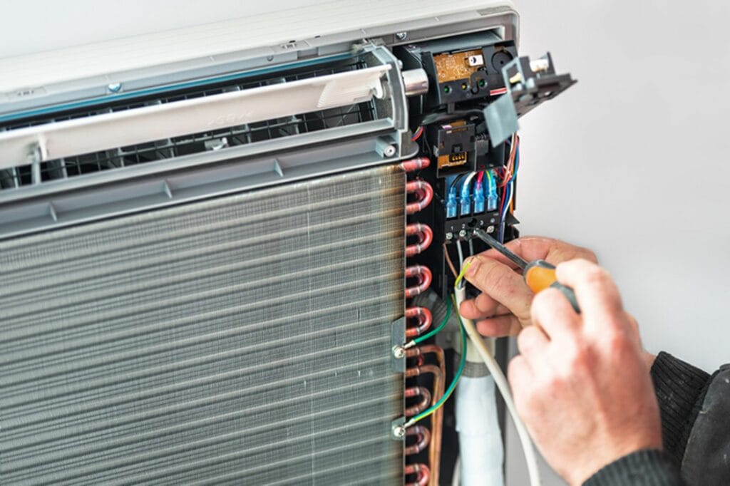 What Should I Do If My AC Breaks Down? Tech's hands repairing AC unit.